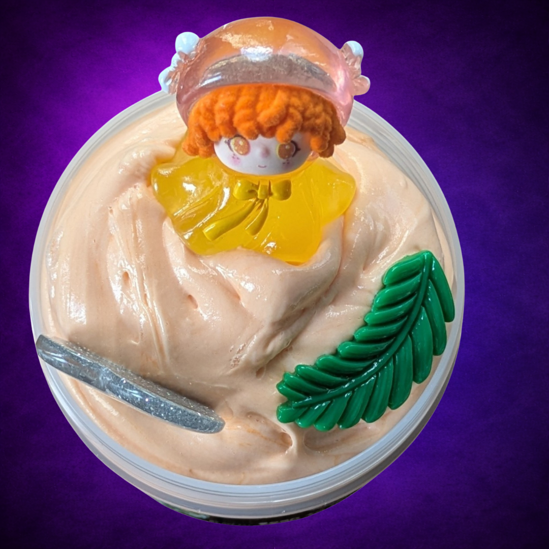 Overhead view of Fódla’s Wish peach-coloured slime with a figure, fern and silver glitter heart.