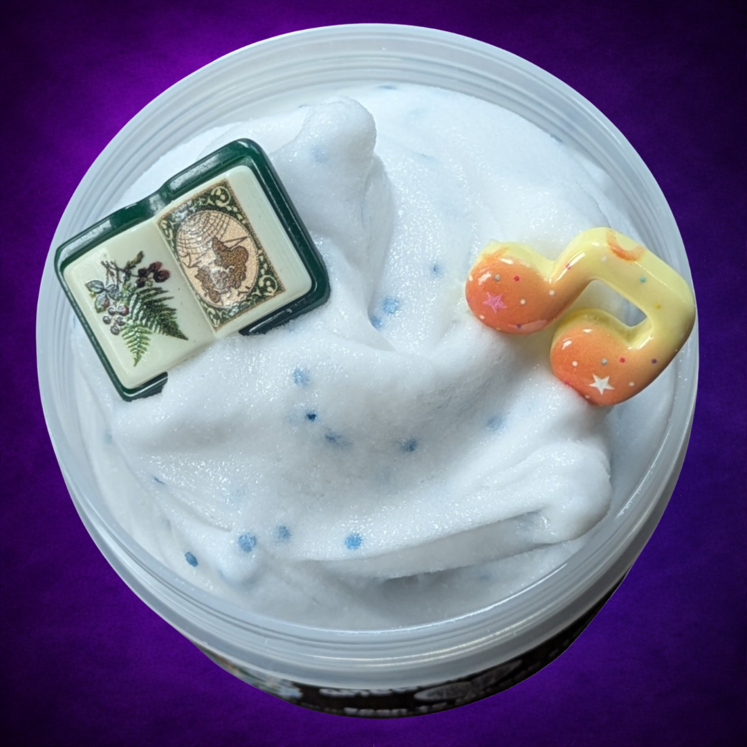 Overhead view of Amergin’s Call white slime with blue glitter, an open storybook and music note.